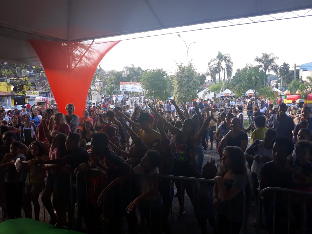 Foto com alguns munícipes presentes no evento, todos em volta do palante durante a realização de brincadeiras e sorteios